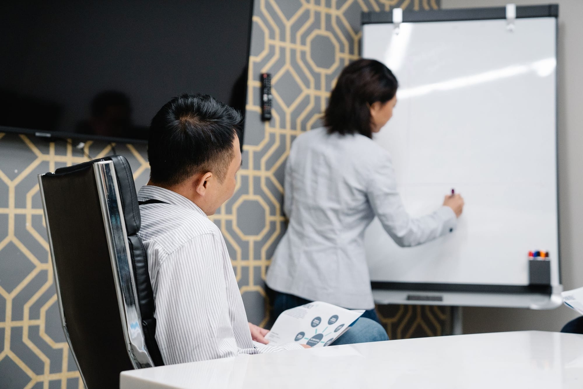 En kvinde skriver på en whiteboard, mens en kollega følger med